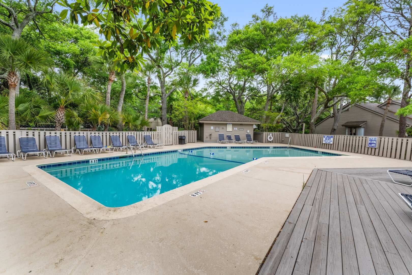 Une piscine rectangulaire avec une terrasse en bois et des chaises longues.