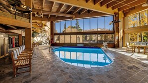 Ein großer, überdachter Pool mit Holzliegen, großen Fenstern und Blick ins Freie.
