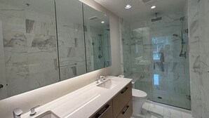 Moderni kylpyhuone, jossa on suuri peili, kaksi pesuallasta, suihku ja wc.