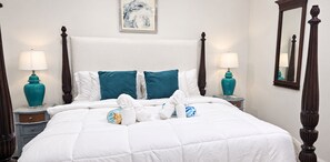 A hotel room with a large bed, two nightstands, a mirror, and a painting on the wall. - Beachside Bliss | 2BR Villa, Pool & Beach Access (Cap Estate)
