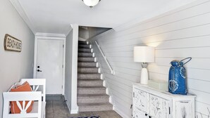 Eine Treppe mit weißer Geländer, eine weiße Tür und ein blauer Vasen auf einem weißen Schrank.