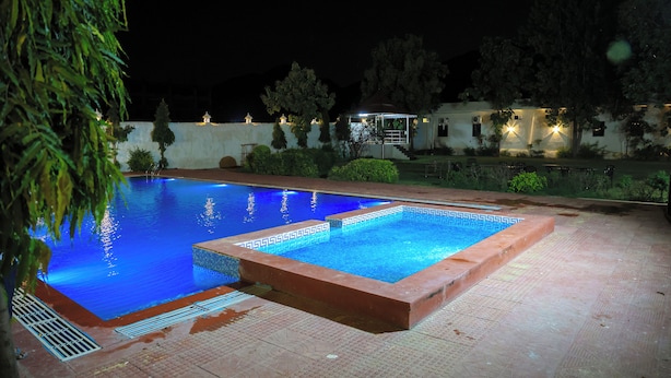 Ein rechteckiger Pool mit Fliesenrand, umgeben von einer gepflasterten Liegefläche.