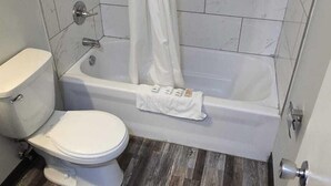 A bathroom with a toilet, bathtub, and shower curtain. - Roblin Motor In (Roblin)