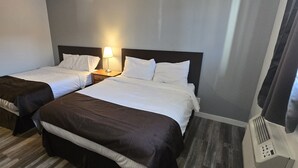 A hotel room with two beds, each with a bedside table and lamp. - Roblin Motor In (Roblin)