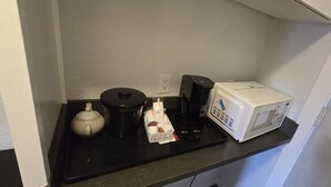A kitchen counter with a kettle, a coffee maker, a microwave, and a carton of milk. - Roblin Motor In (Roblin)