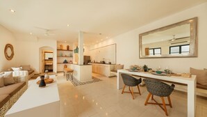 Una sala de estar moderna con sofá, mesa de centro y comedor con sillas.