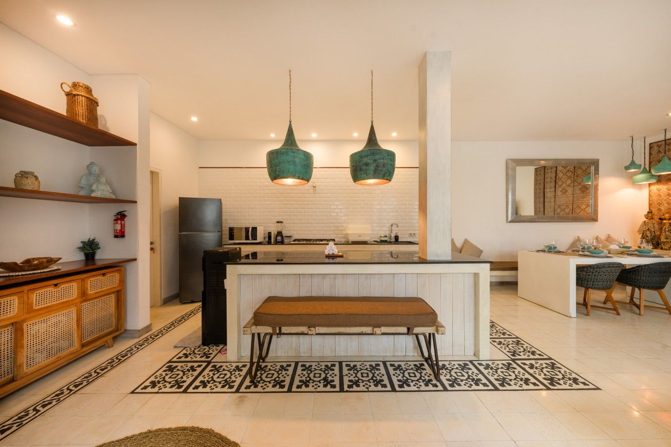 A modern kitchen with a central island, pendant lights, and a dining area with chairs.