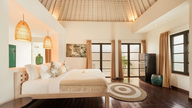 Un dormitorio amplio con una cama grande, techo de madera y vistas a través de puertas de cristal.