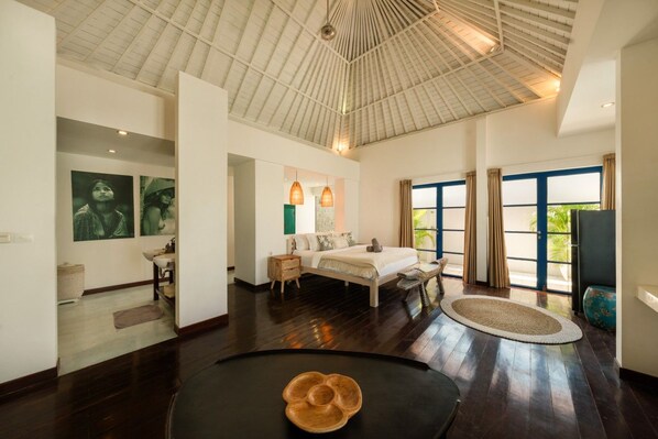 Una habitación amplia con una cama grande, un comedor y vistas a través de un ventanal.