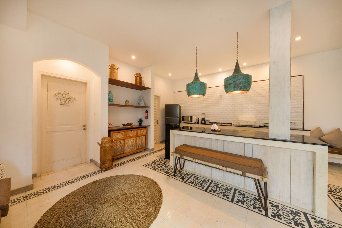 Een moderne keuken met een centraal eiland, hanglampen en een patroonrijk vloerkleed.
