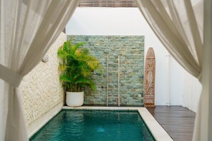 Una piscina con un muro de piedra y una planta en maceta.