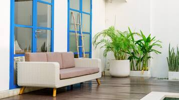 Un espace de détente extérieur moderne, avec un canapé confortable, une échelle en bois et des plantes en pot.