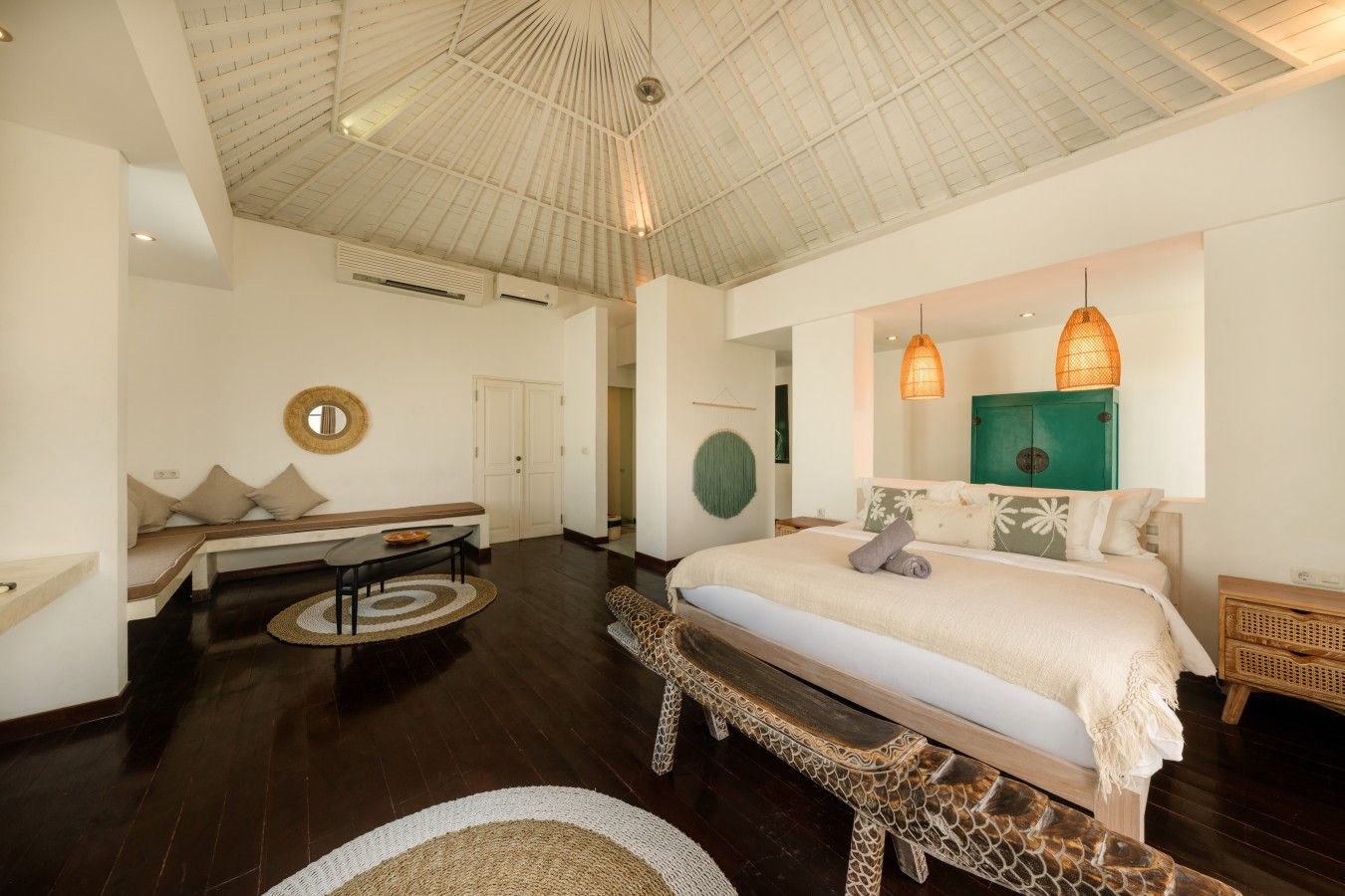 Une chambre dotée d’un grand lit, d’un banc, d’un coin repas et d’un plafond au design original.