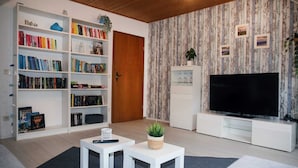 Una sala de estar con una estantería, un televisor y una puerta.