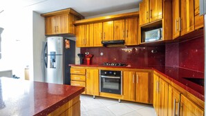A kitchen with wooden cabinets, a stainless steel refrigerator, a microwave, and an oven. - Kaobba Hostal (Medellín)
