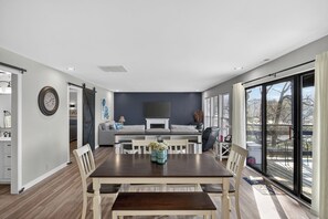 Un salon moderne avec un coin repas, une cheminée et de grandes fenêtres.