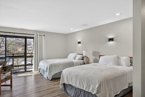 Une chambre d’hôtel avec deux lits, une chaise, une lampe et une vue sur l’extérieur grâce à une grande fenêtre.