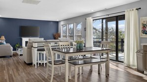 Una sala de estar moderna con comedor, televisor de pantalla plana y chimenea.