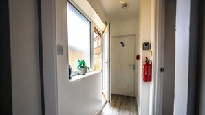 A narrow hallway with a window, a door, and a fire extinguisher mounted on the wall. - Ensuite1 Woodhouse private bath 2kitchen (Stoke-on-Trent)