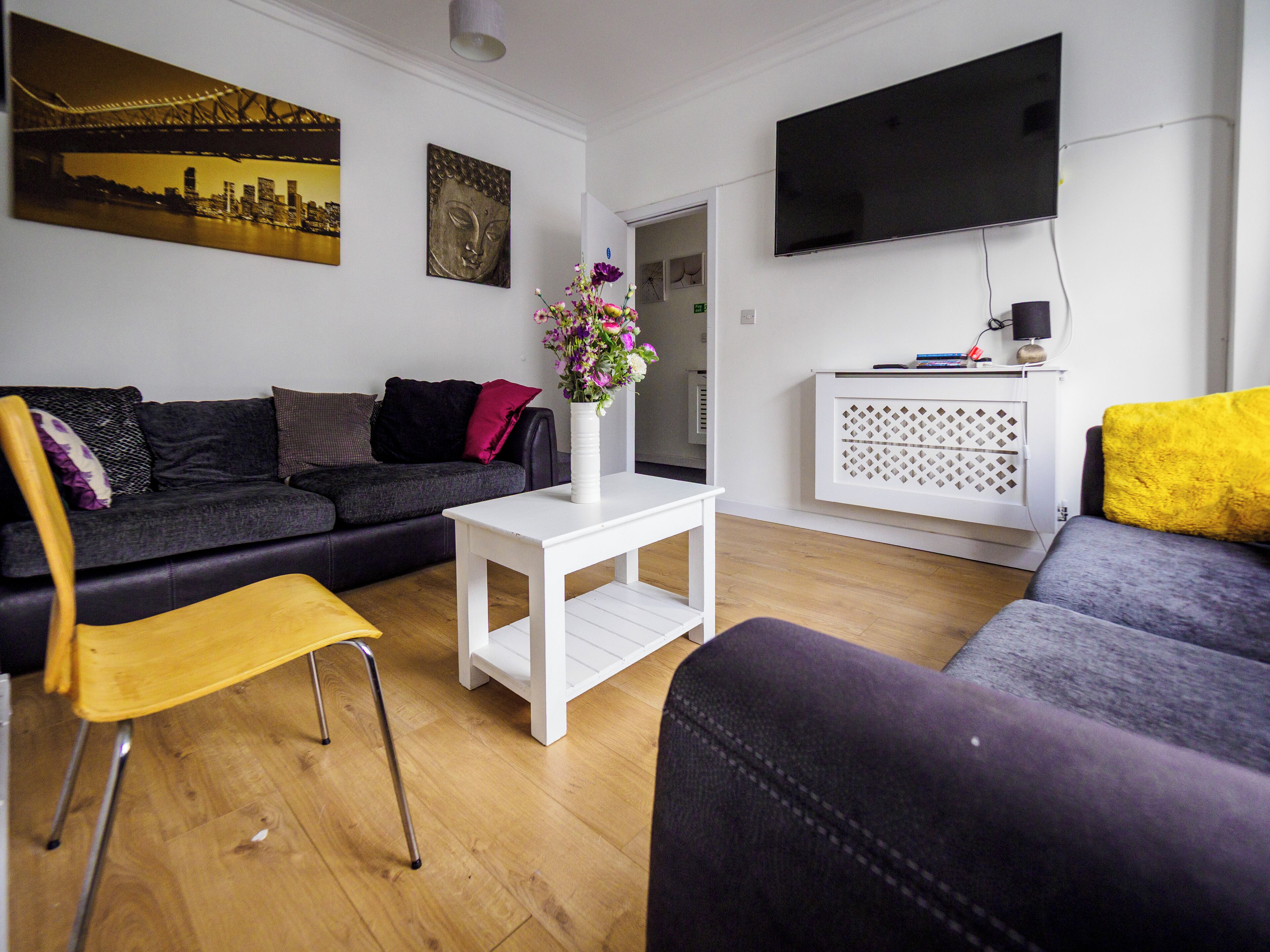 A modern living room with a sofa, a coffee table, and a TV mounted on the wall.