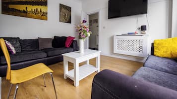 Un salon moderne avec un canapé, une table basse et un téléviseur fixé au mur.