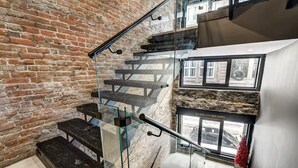 A staircase with glass railings and a brick wall. - AirStay-Saint Paul  (Montréal)