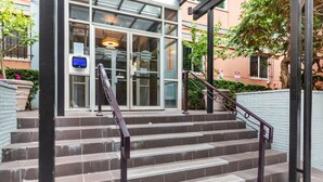 A set of stone steps leading to a building entrance with glass doors and a digital display.