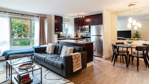 A modern apartment with a living room, kitchen, dining area, and large windows.
