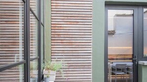 Een modern gebouw met grote ramen, een houten lamellenwand en een deur naar een terras.