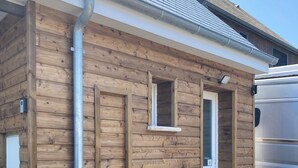 A wooden building with a door, a window, and a metal pipe.