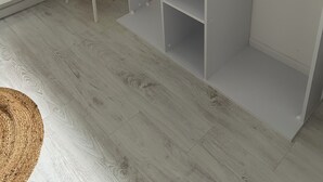 A white room with a wooden floor, a small wooden stool, a grey blanket on a shelf, and wooden hangers on a rack.