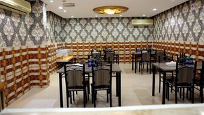 Un restaurante con papel tapiz estampado, diseño de pared que imita ladrillos y varias mesas con sillas.