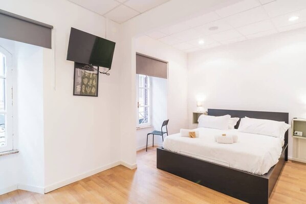 Ein Schlafzimmer mit einem Bett, einem Sessel, einem Fernseher und einem Fenster.