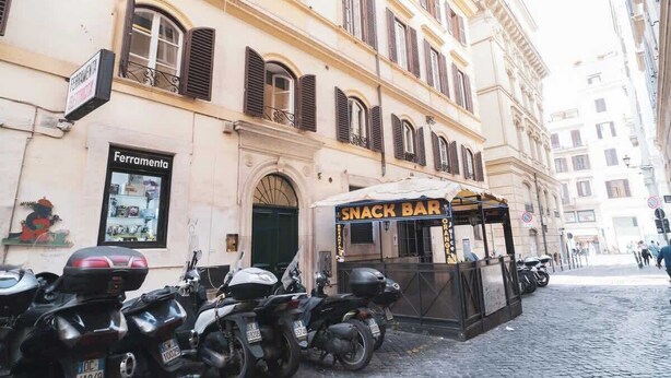 Una calle con motocicletas estacionadas, un bar de tapas y un edificio con un letrero que dice 'Ferramenta'.