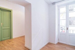 A room with a green door, white walls, and wooden flooring. - BuddyRent - Theo's Trevi - 7 ospiti (Roma)