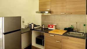 Cocina pequeña equipada con refrigerador, estufa, lavaplatos y alacenas de madera.