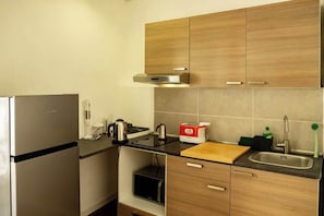 Une cuisine de taille réduite, équipée d’un réfrigérateur, d’une cuisinière, d’un évier et de meubles de rangement en bois.