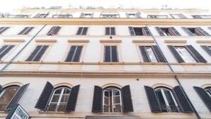A multi-story building with arched windows and shutters, balconies, and a sign indicating a restaurant. - BuddyRent - Theo's Trevi - 7 ospiti (Roma)