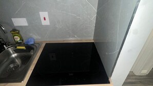 A compact kitchen with a black induction cooktop, a stainless steel sink, and a small countertop.