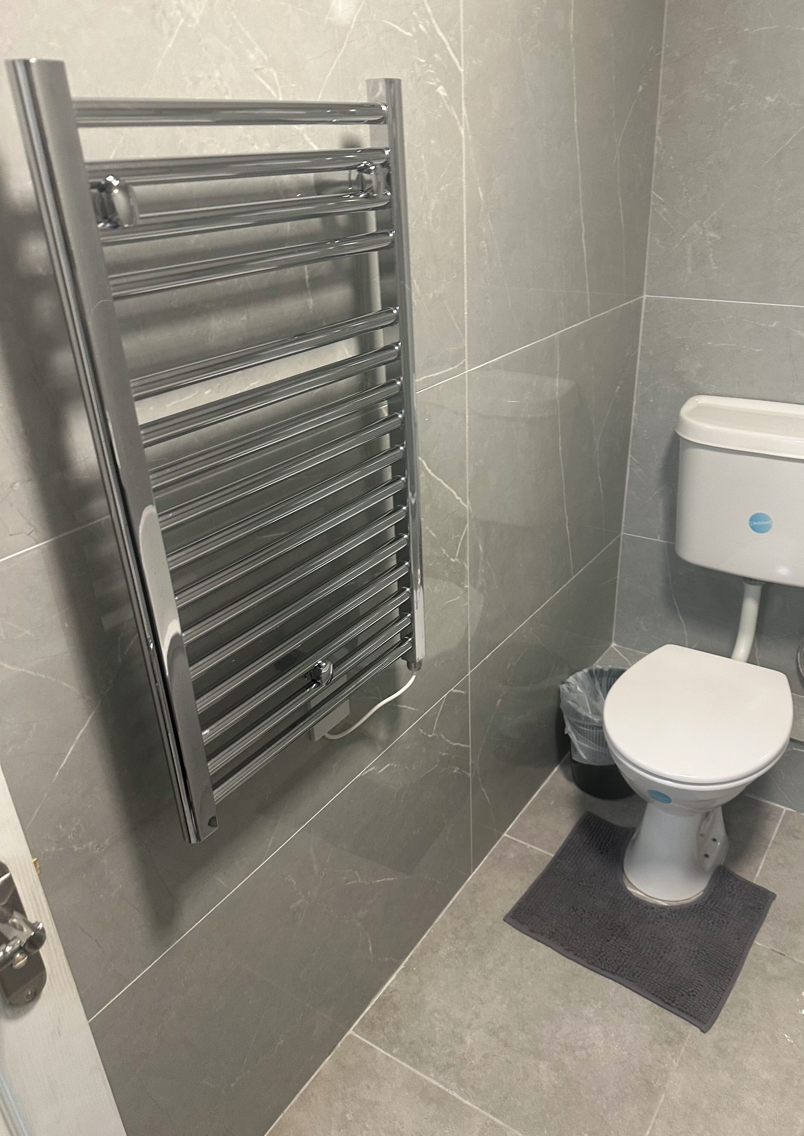 Une salle de bain équipée de toilettes modernes, d’un porte-serviettes en métal et d’une poubelle.
