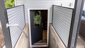 A narrow entrance with a black door, a small potted plant, and a "Hello" mat.