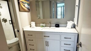 Ein Badezimmer mit weißem Waschtisch, einem großen Spiegel und einer Toilette.
