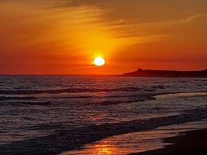A sunset over the ocean with a silhouette of a landmass in the distance. - 🌊 Holiday Home in Erdeven – Walk to the Beach, Heated Pool & Private Garden (Erdeven)