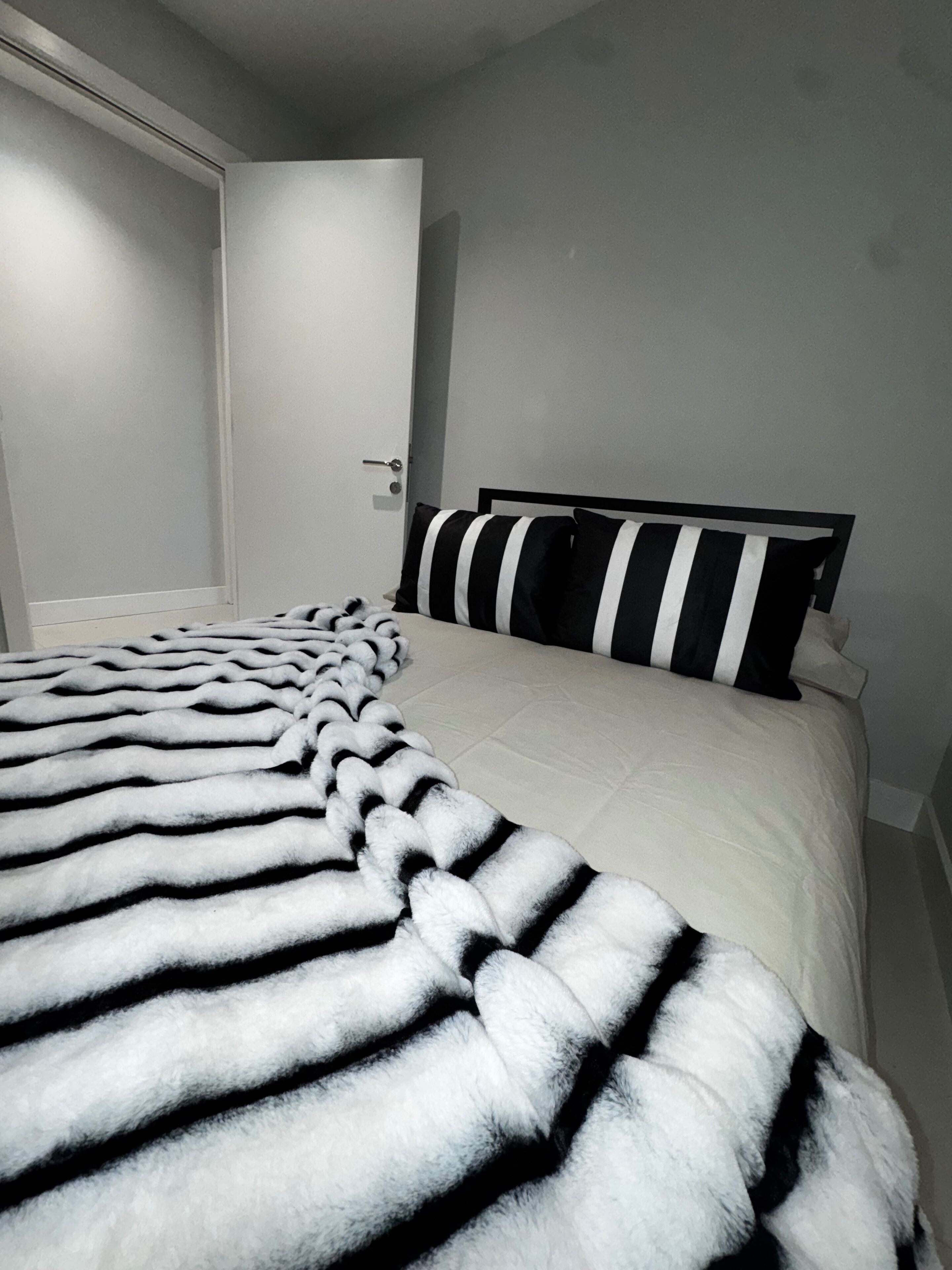 A bedroom with a bed, striped pillows, and a striped blanket.