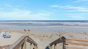 A beach with wooden boardwalks, beach chairs, and umbrellas.