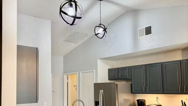 A modern kitchen with a marble island, stainless steel appliances, and black chairs.
