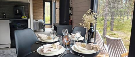 Un comedor con una mesa dispuesta para cuatro personas, una chimenea y vistas al exterior.