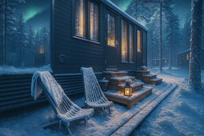 A cabin with a covered porch, two chairs, and a lantern.