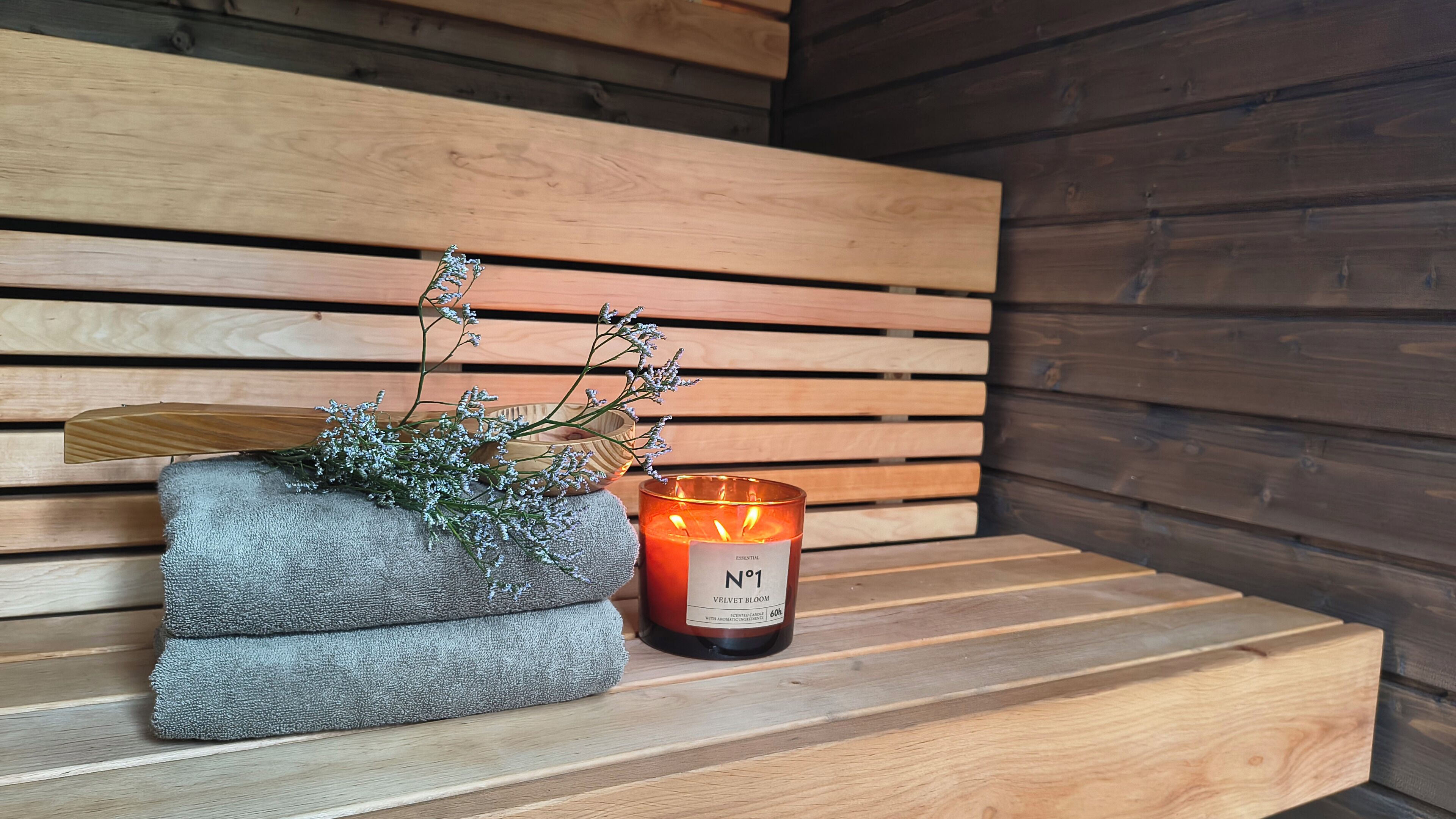 A wooden bench with a candle and a textured planter with small plants.