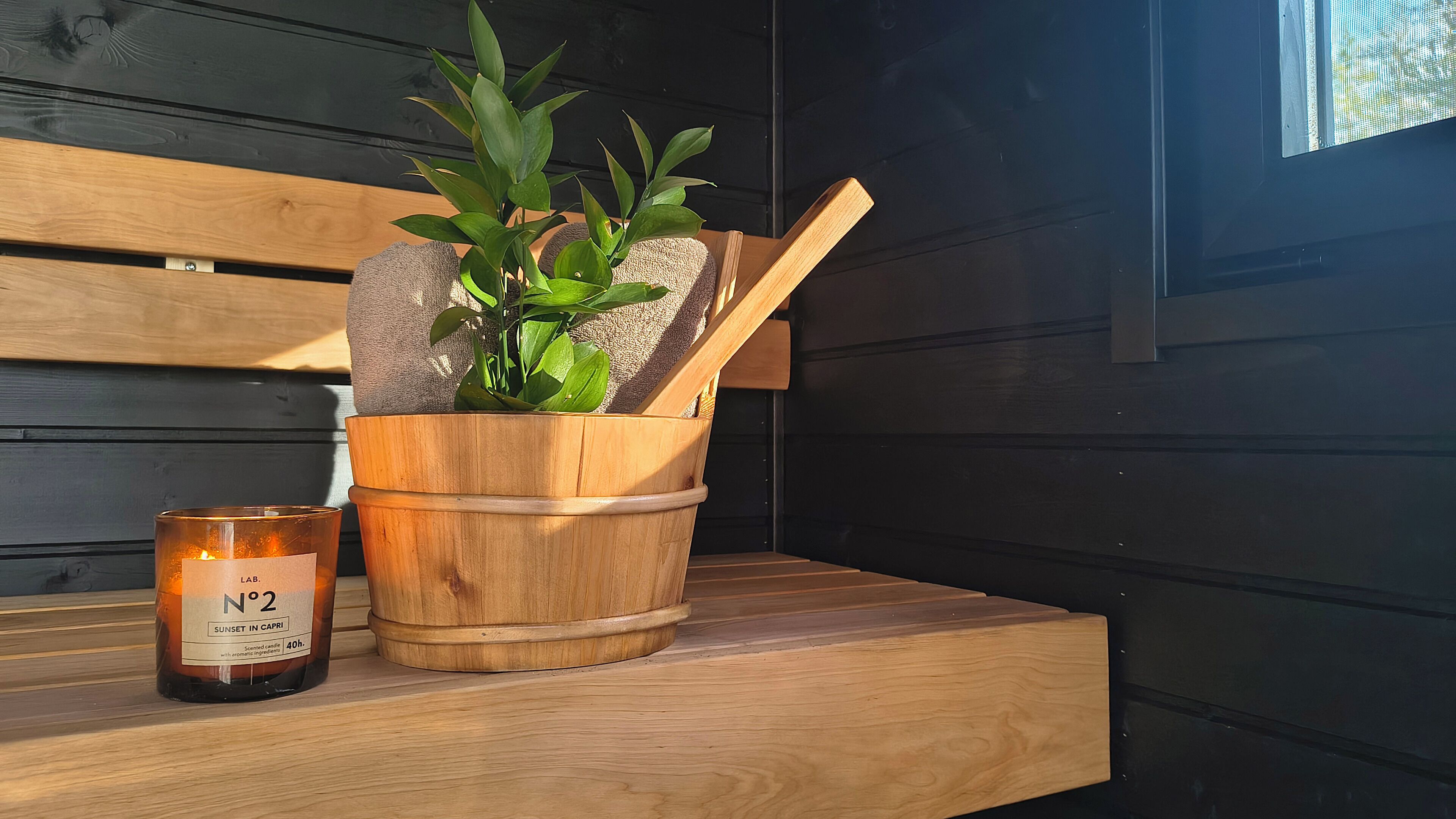 A wooden bench with a potted plant and a candle.